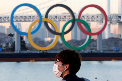 Un hombre con una máscara protectora en medio del brote de coronavirus (COVID-19) frente a los gigantescos anillos olímpicos en Tokio, Japón, el 13 de enero de 2021. REUTERS / Kim Kyung-Hoon