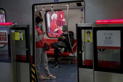 Viajeros con mascarillas leen en sus teléfonos celulares en el metro de Beijing, 10 de febrero de 2021. El organismo supervisor del internet en China obligará a los blogueros e influencers adquieran una licencia para poder publicar opiniones sobre ciertos temas. (AP Foto/Andy Wong)