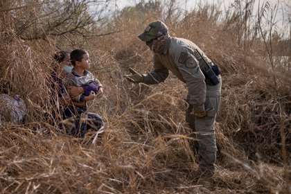 Un policía estatal de Texas pide a los inmigrantes en busca de asilo Edith y su hijo Harbin Ordóñez, de 4 años, que salgan de su escondite después de que los hondureños cruzaron el río Grande hacia los Estados Unidos desde México en una balsa en Peñitas, Texas, el 9 de marzo de 2021 Foto: (REUTERS/Adrees Latif) 