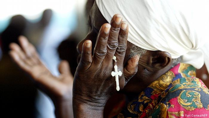 Foto simbólica de una mujer haitiana con un rosario en la mano