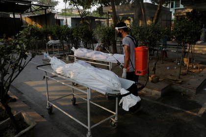 Un empleado municipal traslada los cuerpos de dos víctimas del coronavirus en un crematorio de Nueva Delhi (REUTERS/Adnan Abidi)