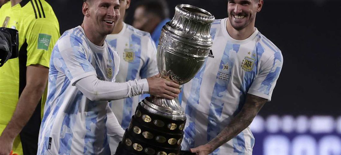 Messi sostiene el trofeo de la Copa América junto a De Paul. Foto: AFP