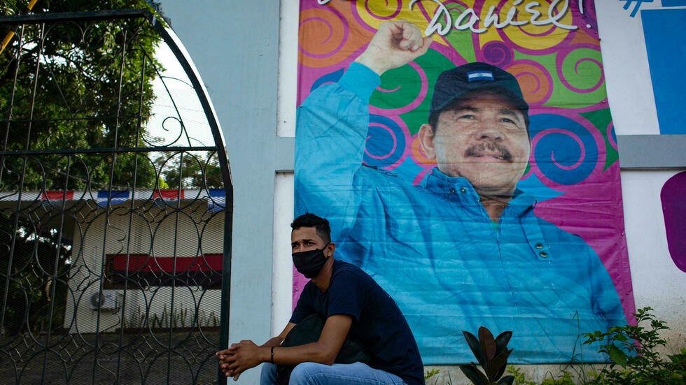Un hombre se sienta frente a una pancarta que promueve la reelección del presidente de Nicaragua, Daniel Ortega, en Managua el 24 de septiembre de 2021.