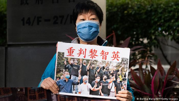 Foto de una persona que sostiene un rótulo en chino que dice fuerte condena contra Jimmy Lai, el periodista encarcelado en China.