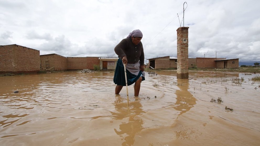 Una mujer camina en medio del agua en las inundaciones en Cliza. APG