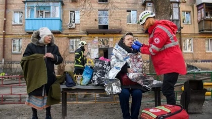Un paramédico ayuda a una mujer herida en el sitio de un distrito residencial de Kiev