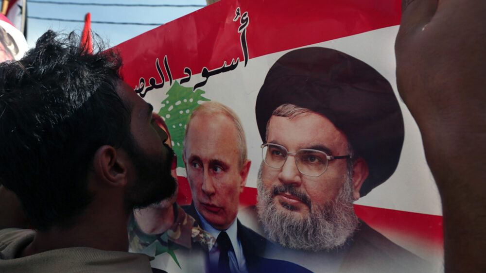 Un militante del grupo terrorista besa una bandera con las imágenes de Putin y Nasrallah (imagen de archivo)