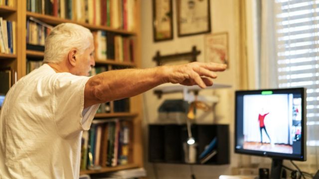 Hombre con parkinson realiza ejercicios viendo una computadora