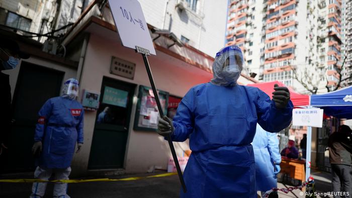 Trabajadores en trajes de bioseguridad dan instrucciones a los residentes de Shanghái a la espera de hacerse un test anticovid.