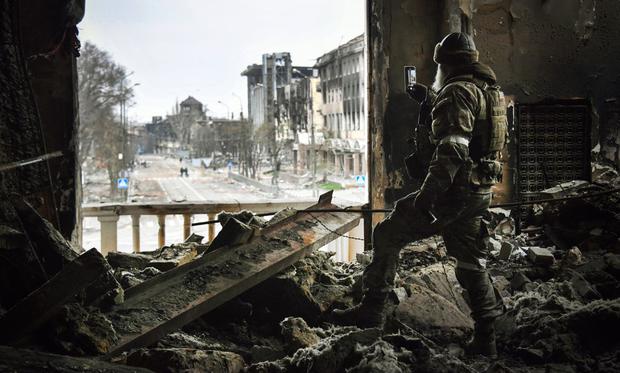 Un soldado ruso patrulla en el teatro de drama de Mariupol, bombardeado el 16 de marzo pasado. (Alexander NEMENOV / AFP).