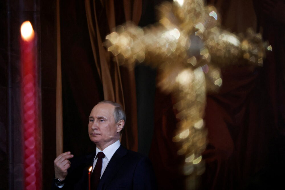 El jefe de estado ruso Vladimir Putin sostiene una vela mientras asiste al servicio de Pascua ortodoxa en la Catedral de Cristo Salvador en Moscú, Rusia. La maquinaria estatal de propaganda es la encargada de difundir teorías conspirativas para justificar la inivasión a Ucrania (Reuters)