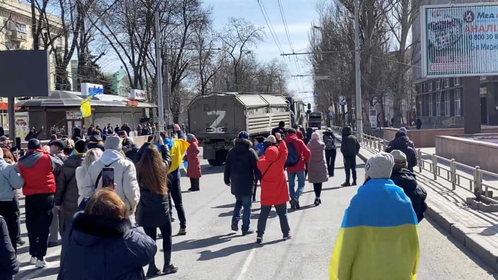 FOTO DE ARCHIVO: Manifestantes, algunos mostrando banderas ucranianas, corean "ir a casa" mientras los vehículos militares rusos invierten su curso en la carretera, en una manifestación a favor de Ucrania en medio de la invasión de Rusia, en Kherson, Ucrania 20 de marzo de 2022 en esta imagen fija de un video obtenido por REUTERS
