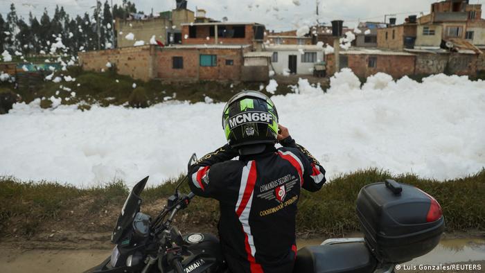 Un motociclista toma fotos con su móvil de la espuma contaminante.