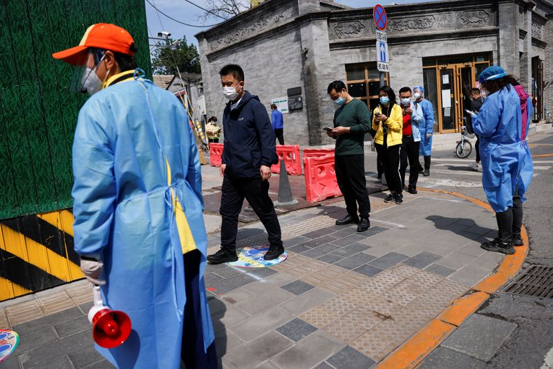 Varias personas con mascarilla esperan en fila a ser sometidos a un test de COVID-19 en Shanghái, China, el 11 de mayo de 2022. REUTERS/Carlos Garcia Rawlins