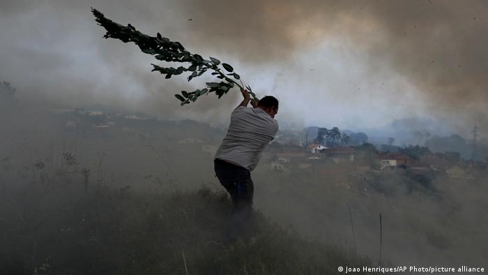 Foto de una persona que intenta sofocar las llamas con unas hojas en Portugal en una imagen de archivo.