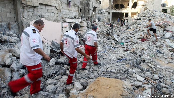 Trabajadores de la Media Luna Roja buscan víctimas entre los escombros, en la Franja de Gaza, luego de bombardeos israelíes.