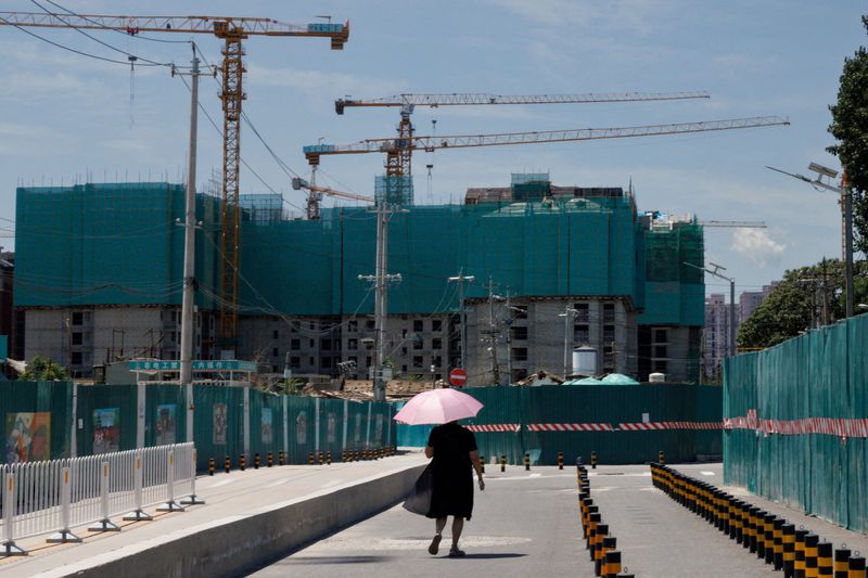 Una mujer camina cerca de un sitio de construcción de edificios de departamentos en Beijing (REUTERS/Thomas Peter/Foto de archivo)