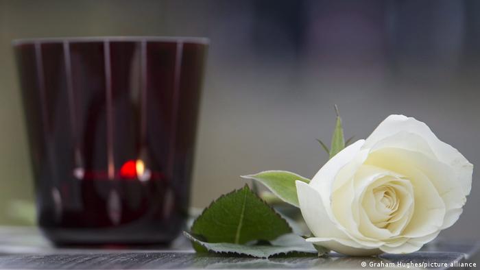 Foto de una vela y una rosa blanca en señal de luto en una imagen de archivo.