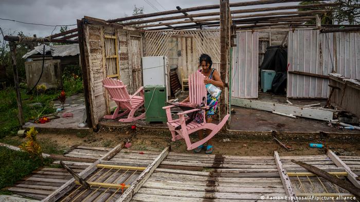 Una mujer intenta recuperar sus pertenencias de lo que queda de su casa tras el paso del huracán Ian.