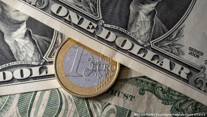 Moneda de un euro entre billetes de un dólar.