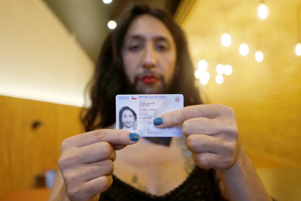 Shane Cienfuegos posa para fotografías después de recibir su cédula de identidad que le reconoce como una persona trans no binaria, en Santiago de Chile (EFE/Felipe Poga)