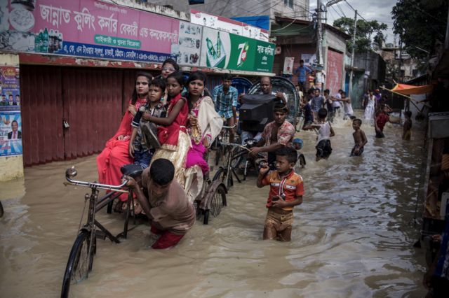 Personas moviendo sus pertenencias en una calle de Chittagong