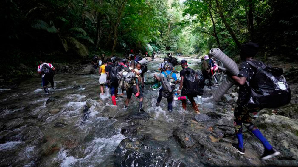 Migrantes cruzan un río en su viaje hacia el norte, cerca de Colombia