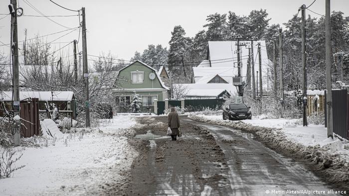 Un ciudadano camina entre la nieve en la aldea de Moschun, que ha sido destruida como resultado del intenso bombardeo del ejército ruso, ahora las condiciones de vida se vuelven más difíciles con las primeras nevadas.