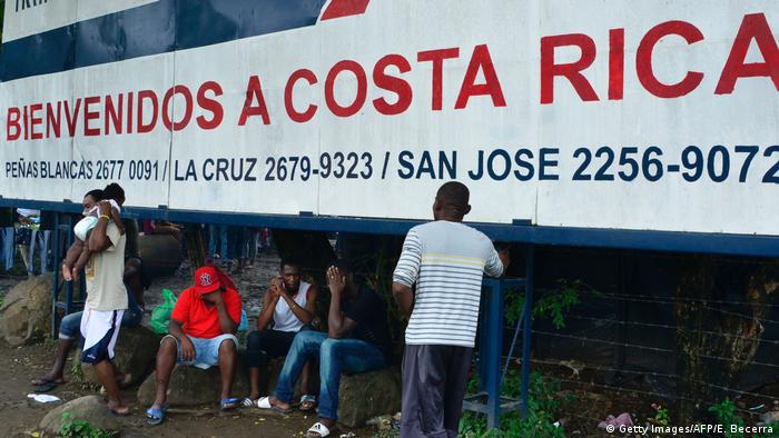 Foto de archivo de personas migrantes frente a un rótulo que dice Bienvenidos a Costa Rica