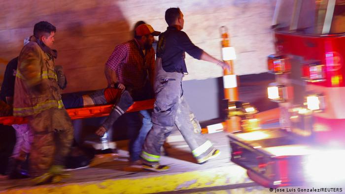 Una persona es llevada en camilla junto a un camión de bomberos.