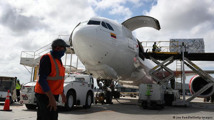 Trabajadores cargan con cajas un avión en el aeropuerto de Miami.