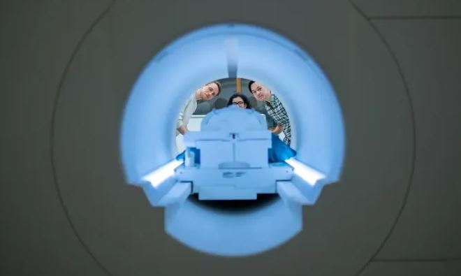 Alex Huth (izquierda), Shailee Jain (centro) y Jerry Tang (derecha) se preparan para recopilar datos de actividad cerebral en el Centro de Imágenes Biomédicas de la Universidad de Texas en Austin (Nolan Zunk/Universidad de Texas en Austin)