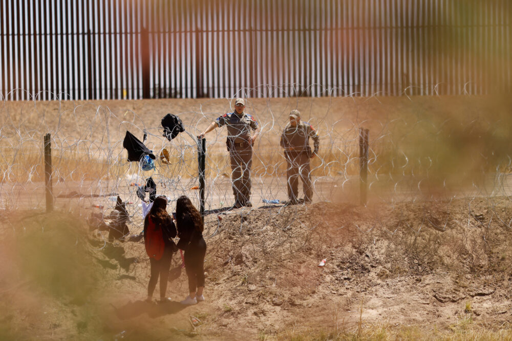 Migrantes se paran cerca del muro fronterizo después de haber cruzado la frontera entre Estados Unidos y México para entregarse a los agentes de la Patrulla Fronteriza de Estados Unidos. REUTERS/José Luis González