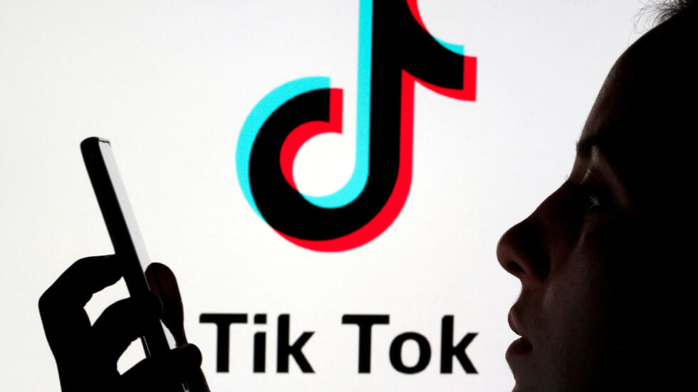 (foto de ilustración) Una persona sostiene un teléfono inteligente mientras detrás se muestra el logotipo de Tik Tok. Fotografía tomada el 7 de noviembre de 2019.