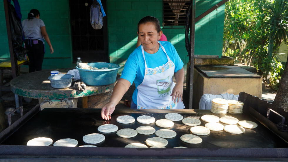 Lucia Alvayero, de 46 años, hace tortillas en un puesto en la calle en el barrio La Campanera, Soyapango, el 4 de febrero de 2024 durante las elecciones para presidente y diputados en esta zona donde operaba la pandilla Barrio 18 que fue desterrada por la guerra del presidente Nayib Bukele