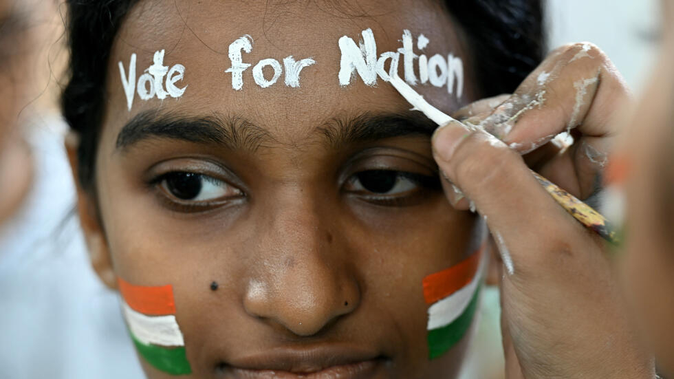 Una estudiante de una escuela de arte se pinta la cara con la bandera india y el mensaje "Vota por la nación" para alentar a la población a votar en las elecciones generales de India, en Bombay, el 17 de abril de 2024