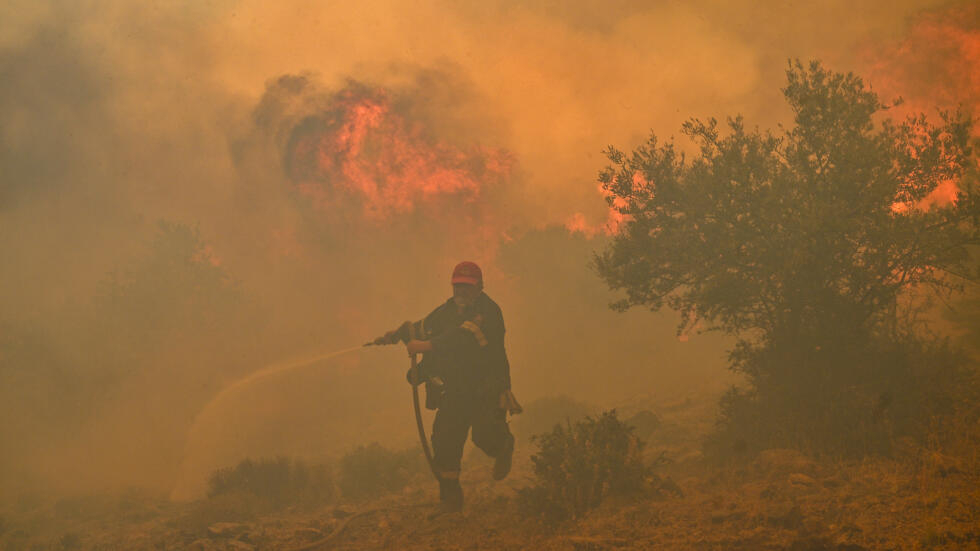 Un bombero huye de las llamas de un incendio en Néa Péramos, cerca de Atenas, el 19 de julio de 2023