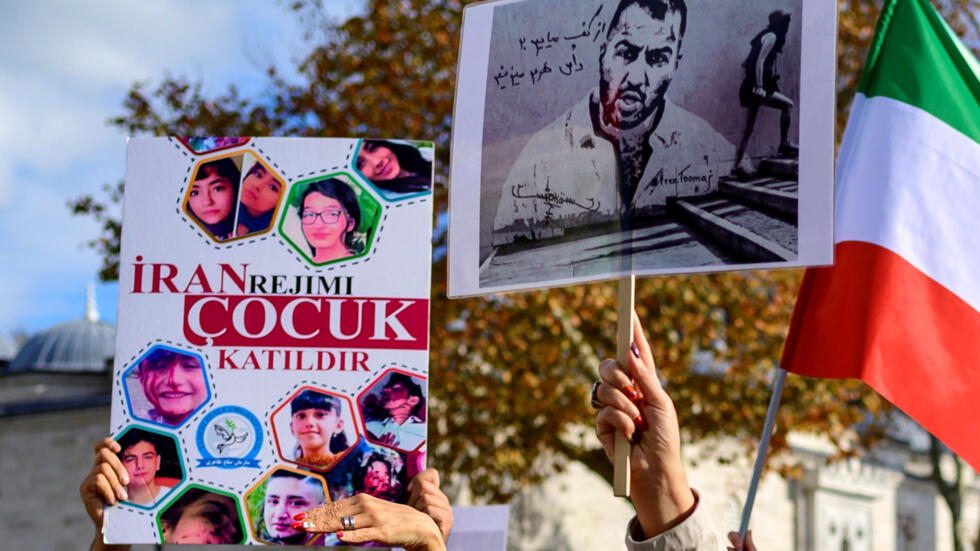 Unas manifestantes muestran un retrato del rapero Toomaj Salehi (drcha.) y de unos niños muertos en las protestas en Irán, el 26 de noviembre de 2022 en Estambul