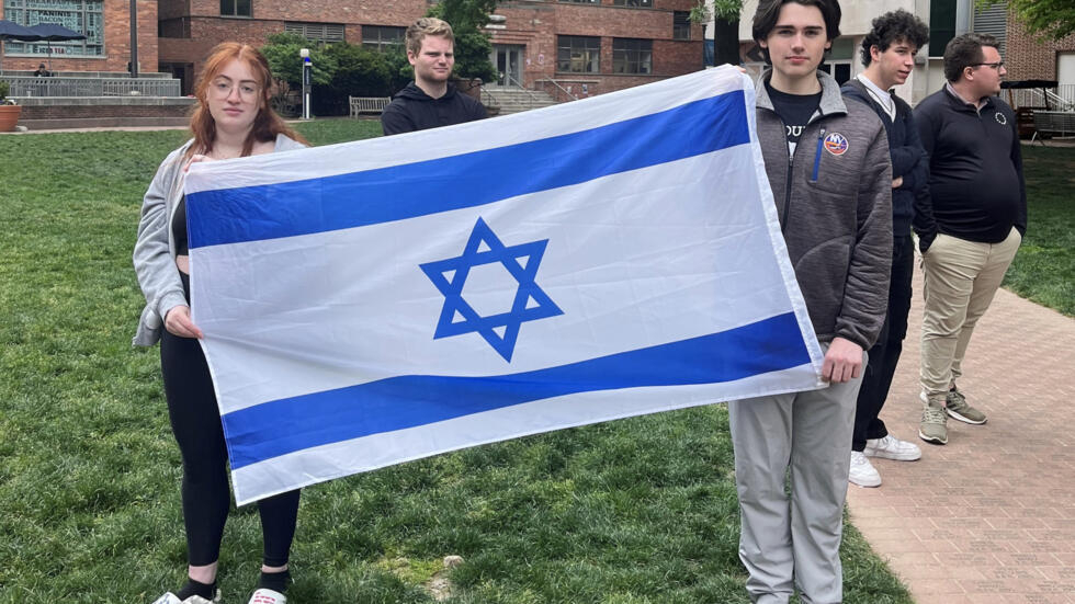 La estudiante de filosofía Skyler Sieradzky (I) sostiene una bandera de Israel mientras manifestantes propalestina hacen una sentada en el campus urbano de la Universidad George Washington, en Washington