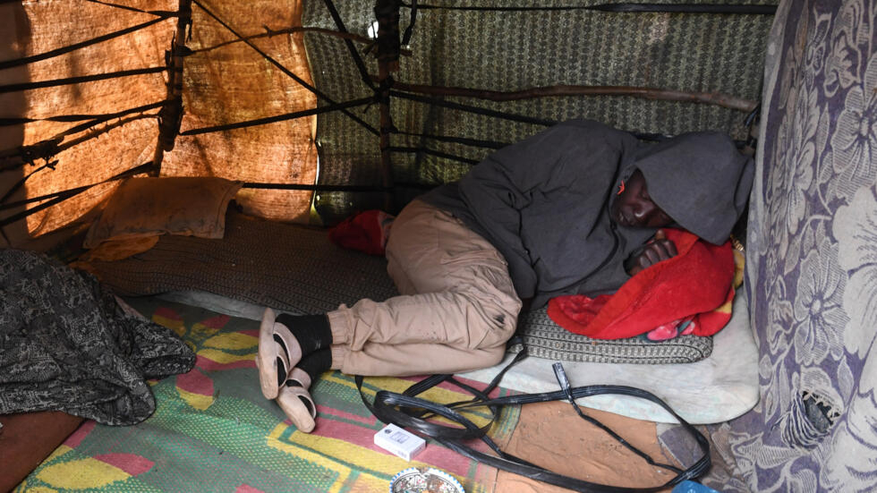 Un migrante subsahariano descansa en una tienda de campaña improvisada en el campo de Jebeniana, en la provincia de Sfax, el 24 de abril de 2024 al este de Túnez