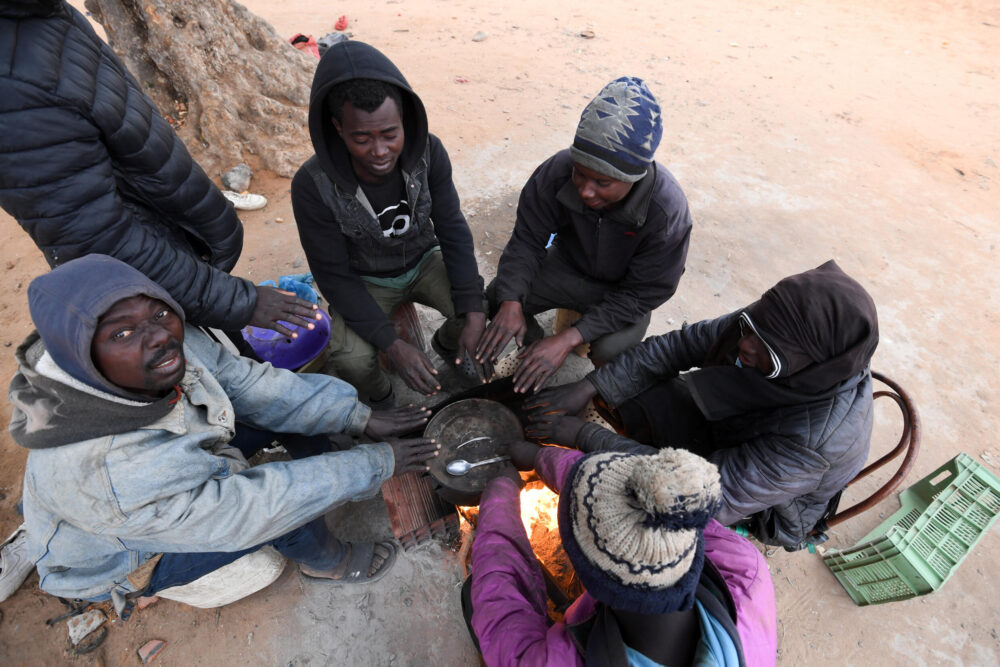 Unos migrantes subsaharianos se reúnen en torno a un pequeño fuego en el campo de Jebeniana, en la provincia de Sfax, el 24 de abril de 2024 al este de Túnez