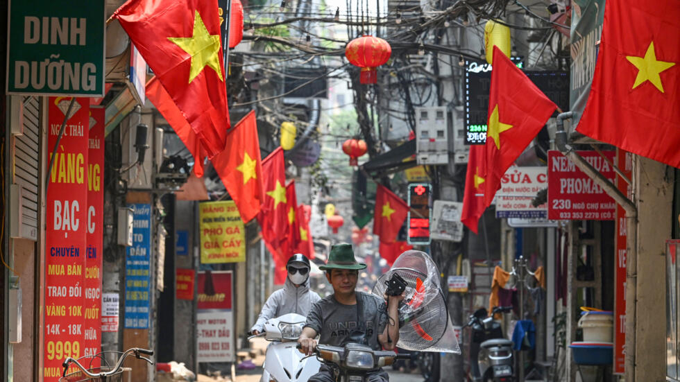 Un hombre lleva un ventilador en una motocicleta por una calle de Hanói, en un caluroso 30 de abril de 2024 en la capital vietnamita