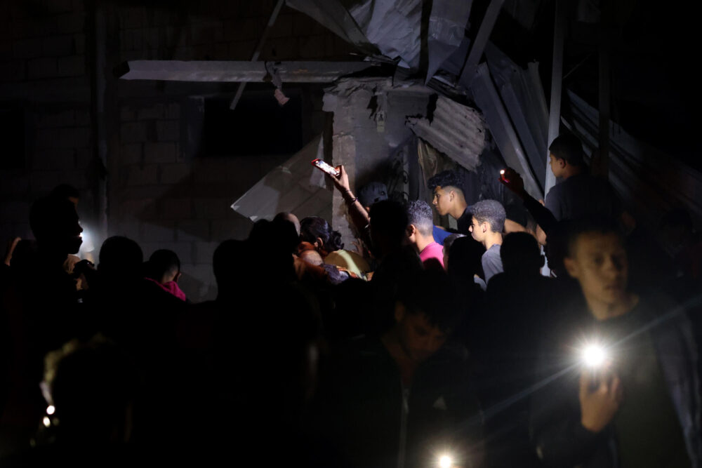 Unos palestinos utilizan las luces de sus teléfonos móviles para buscar a supervivientes entre los escombros de un edificio bombardeado por Israel en Rafah, en el sur de la Franja de Gaza, el 7 de mayo de 2024