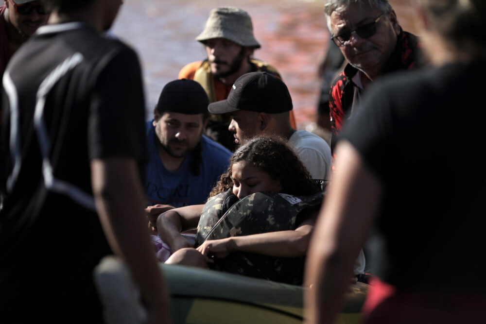 Unos voluntarios forman una cadena humana para recibir las barcas con personas evacuadas de áreas inundadas en el barrio de Sao Joao, en la ciudad brasileña de Porto Alegre, en el estado de Rio Grande do Sul, el 7 de mayo de 2024