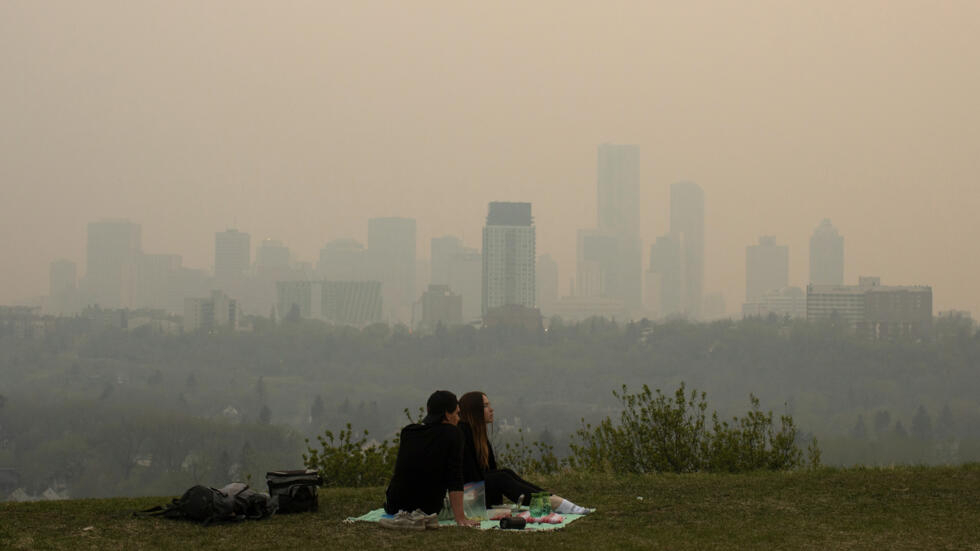 El humo de los incendios forestales cubre la ciudad mientras una pareja hace un picnic en Edmonton, Alberta, el sábado 11 de mayo de 2024.