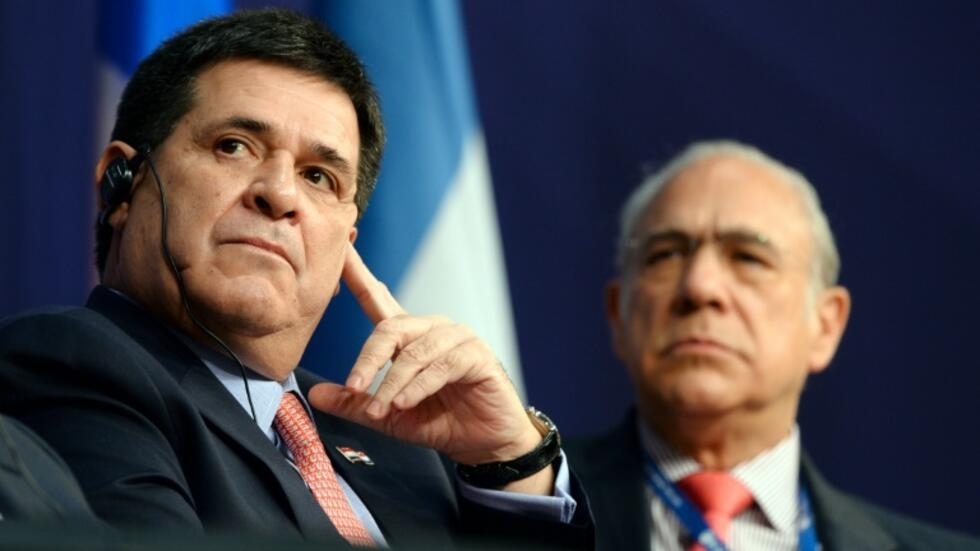 El presidente de Paraguay, Horacio Cartes, flanqueado por el secretario general de la OCDE, Ángel Gurría (R), escucha un discurso durante el foro económico internacional de América Latina y el Caribe en el Ministerio de Economía, en París, el 3 de junio de 2016.