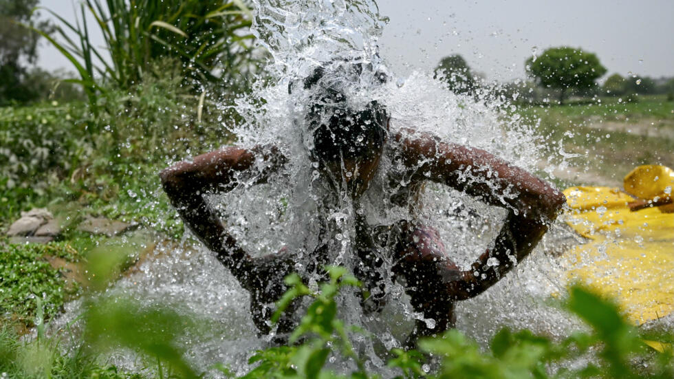 Una persona se refresca con el agua que emana de una tubería en las vegas del río Yamuna en Nueva Delhi, donde las temperaturas alcanzan un récord el 29 de mayo de 2024