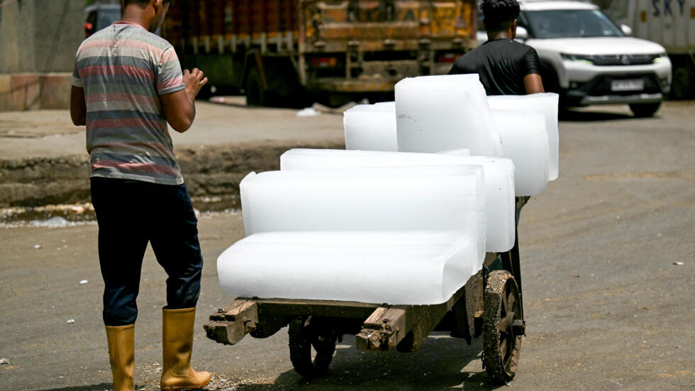Dos trabajadores transportan bloques de hielo en un carro en Nueva Delhi el 30 de mayo de 2024, en plena ola de calor