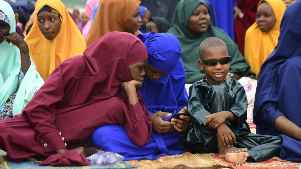 Unas jóvenes miran un teléfono móvil durante la oración del Eid al Fitr en Maiduguri, Nigeria, el 10 de abril de 2024