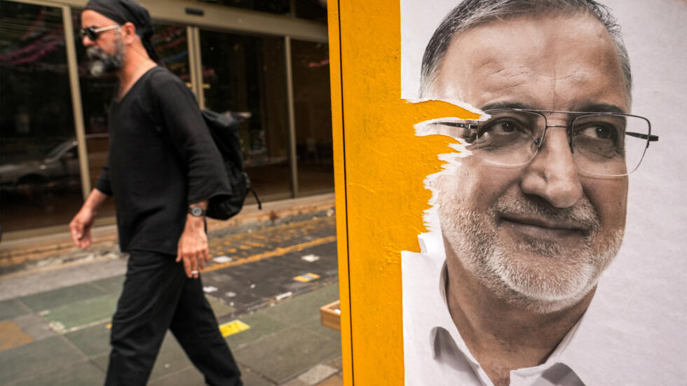 Un hombre pasa junto a un cartel electoral de Alireza Zakani, alcalde de Teherán y candidato a la presidencia, el 23 de junio de 2024 en la capital iraní